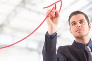 Businessman drawing a rising arrow, representing business growth.